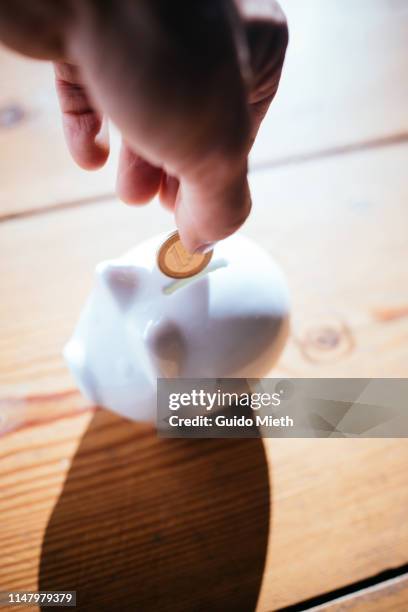 putting a coin to savings. - women euro stock-fotos und bilder