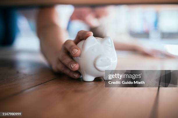 woman finding piggy bank under sofa. - hiding money stock pictures, royalty-free photos & images