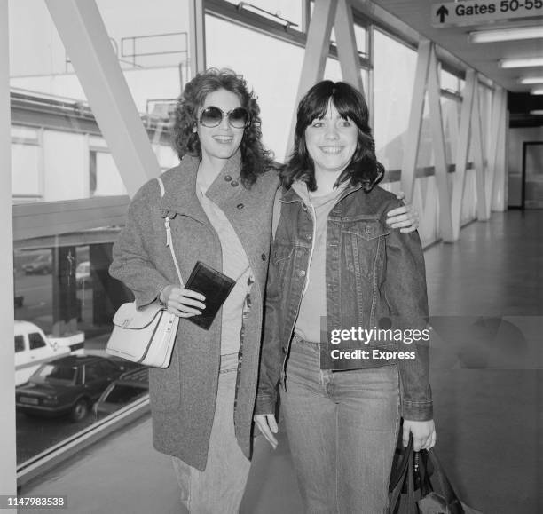 American singer, songwriter and musician Emmylou Harris with her daughter Mika Hallie Slocum at Heathrow Airport, London, UK, 15th April 1984.