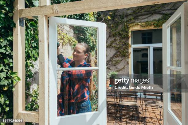 woman installing a door in diy greenhouse. - large group of craftsman stock-fotos und bilder