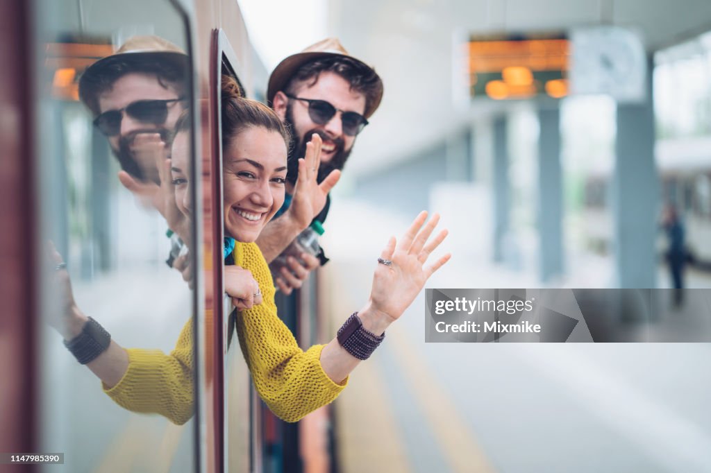 Joven pareja saludando desde la ventana del tren