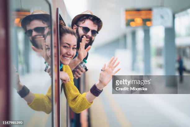 young couple waving from the train window - platform shoe stock pictures, royalty-free photos & images