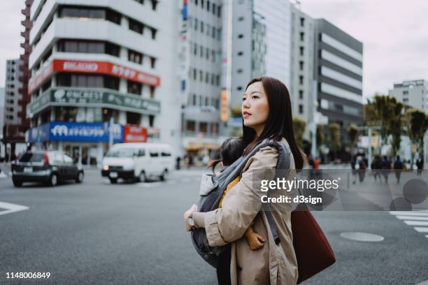 young asian working mother crossing street and commuting in busy downtown city with little daughter - japanese mom stock pictures, royalty-free photos & images
