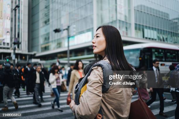 young asian working mother crossing street and commuting in busy downtown city with little daughter in rush hour - ein tag im leben stock-fotos und bilder