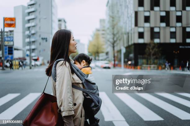 young asian working mother crossing street and commuting in busy downtown city with little daughter - working mother - fotografias e filmes do acervo