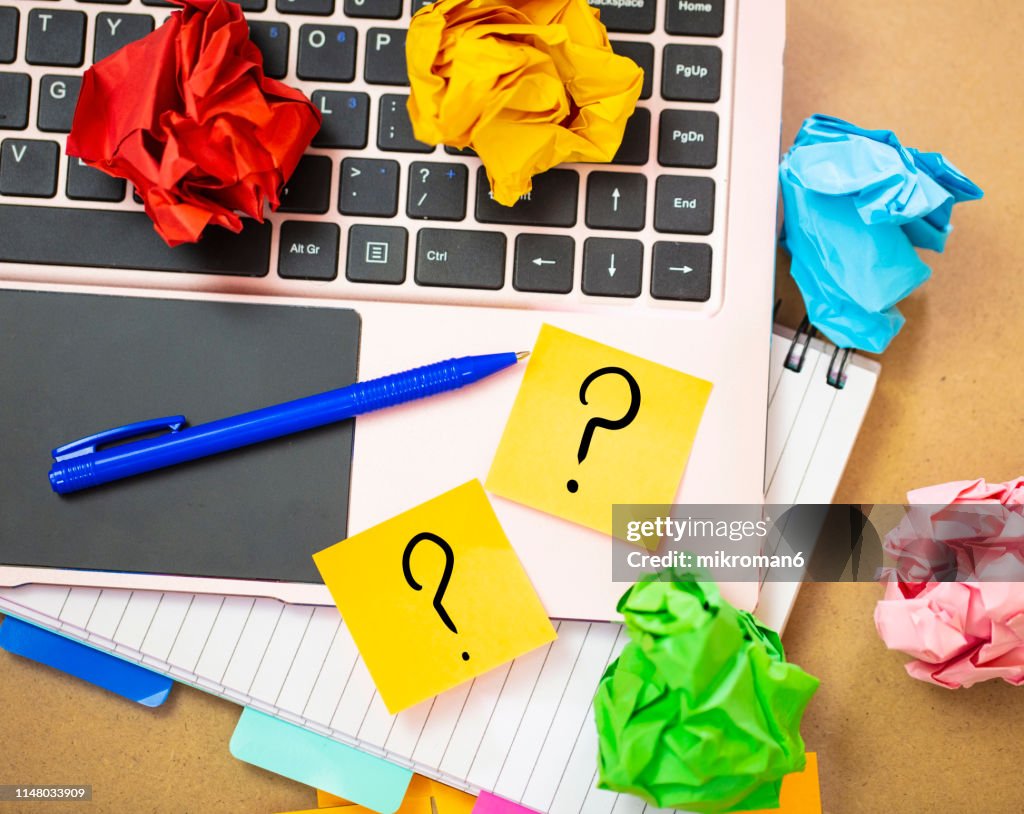 Office work with laptop and sticky notes with question mark