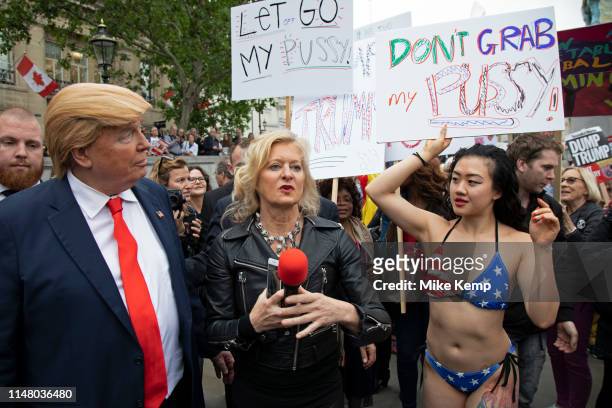 Donald Trump lookalike interacts with a bikini wearing protester who is holding a placard which reads 'Don't grab my pussy' in Trafalgar Square...