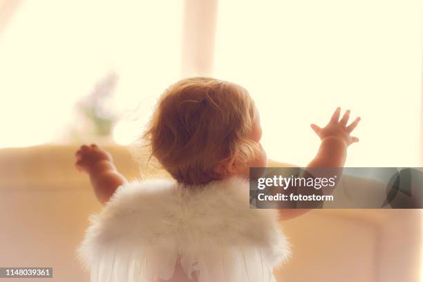 baby girl with angel wings raising her hands - baby angel wings stock pictures, royalty-free photos & images