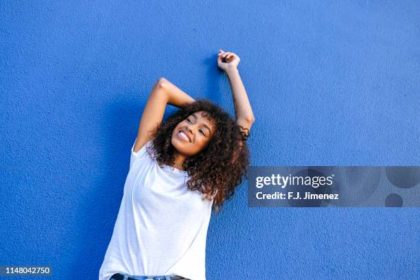 portrait of smiling woman with blue background - t shirt stock-fotos und bilder