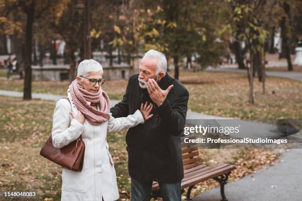 couple d’âge mûr ayant un débat dans le parc public - communication problems photos et images de collection