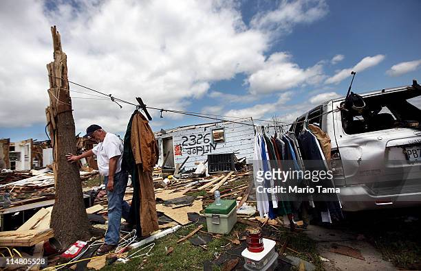 Jim Burd's walks past his clothes hanging on a line outside his destroyed home after a massive tornado passed through the town killing at least 125...