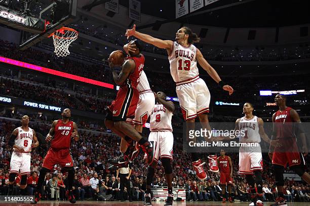 LeBron James of the Miami Heat is on the receiving end of a flagrant foul by Carlos Boozer of the Chicago Bulls as Joakim Noah of the Bulls also...