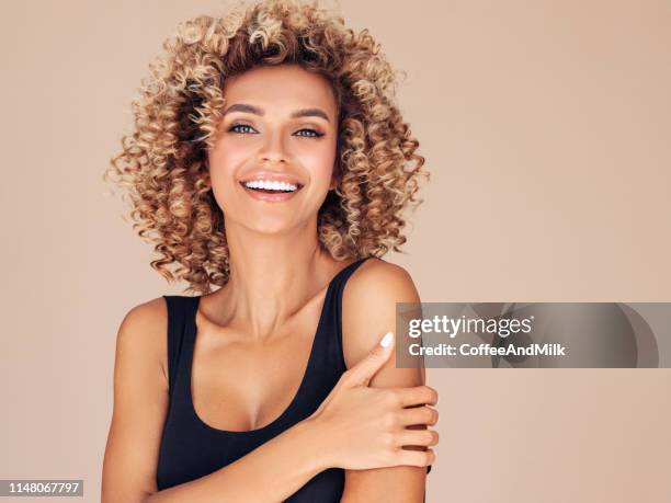 schöne junge frau mit lockigen haaren - afro hairstyle stock-fotos und bilder