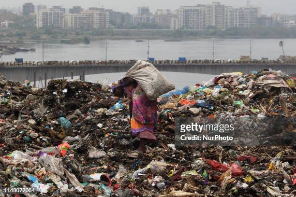 Woman stands on a pile up garbage as she collects recyclable material at a garbage dump ahead of World Environment Day at the outskirts of Mumbai,...