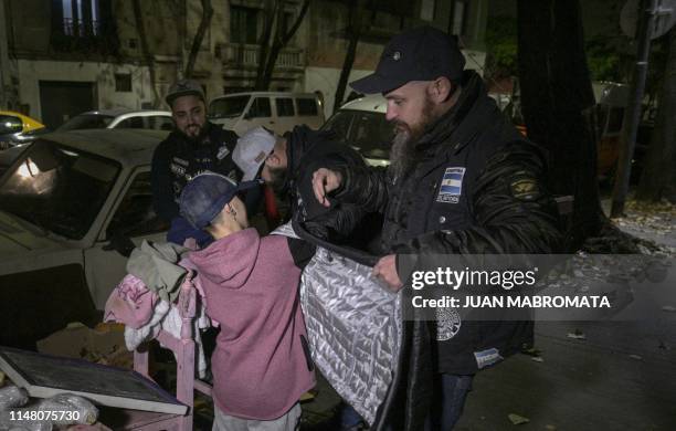 Members of Bearded Villains Argentina, also known as "Villanos del fin del mundo" try a jacket on Ezequiel -who lives in the street with his family-...