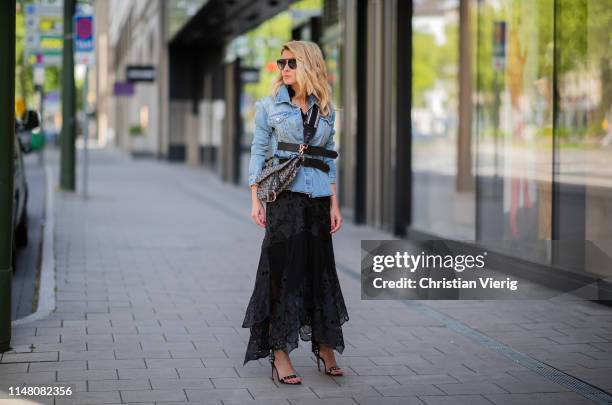 Gitta Banko is seen wearing a black lace tulle ruffle dress by Jonathan Simkhai, a blue cotton double buckle denim jacket from RtA, black sandals...
