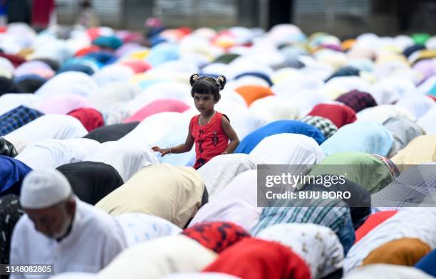 An Indian Muslim child stands as devotees offer prayers during Eid al-Fitr at the Idgah field in Guwahati on June 5, 2019. - Muslims around the world...