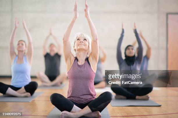 raising their arms - senior yoga stock pictures, royalty-free photos & images