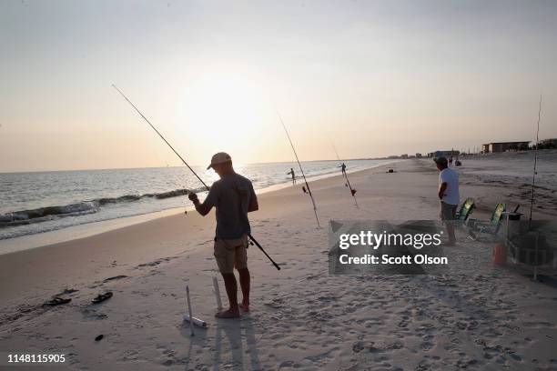 Scott Bodiford and Andy Crick relax by fishing on the beach after spending the day restoring homes that were damaged by Hurricane Michael on May 09,...