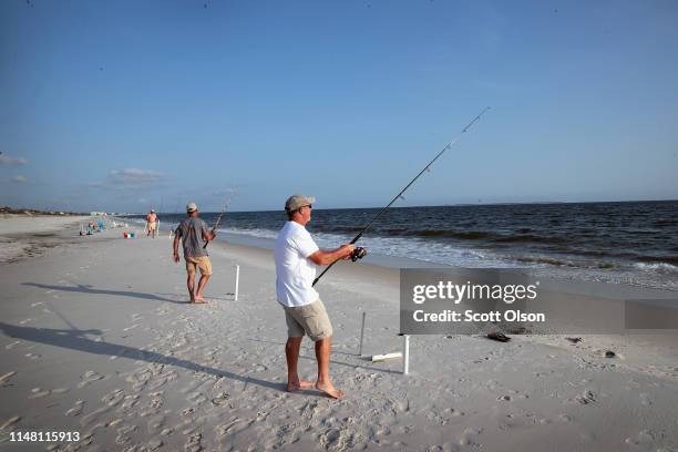 Scott Bodiford and Andy Crick relax by fishing on the beach after spending the day restoring homes that were damaged by Hurricane Michael on May 09,...