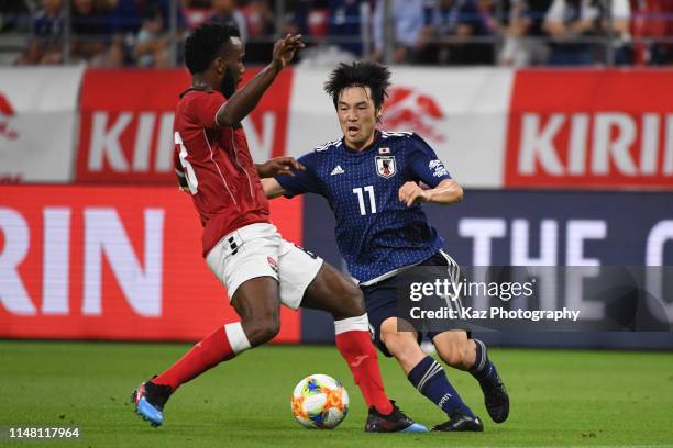 Shoya Nakajima of Japan shoots and Khaleem Hyland of Trinidad and Tobago compete for the ball during the international friendly match between Japan...