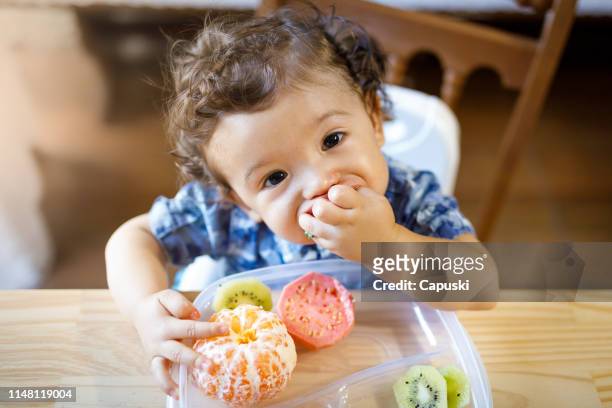 baby boy eating tasty fruit - baby eating food imagens e fotografias de stock
