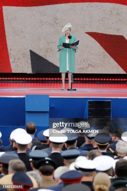 Britain's Prime Minister Theresa May stands and speaks as she reads a letter written by Captain Skinner, during an event to commemorate the 75th...