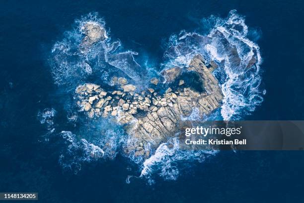 ocean waves crashing over heart-shaped rock island - heart shape in nature stock pictures, royalty-free photos & images
