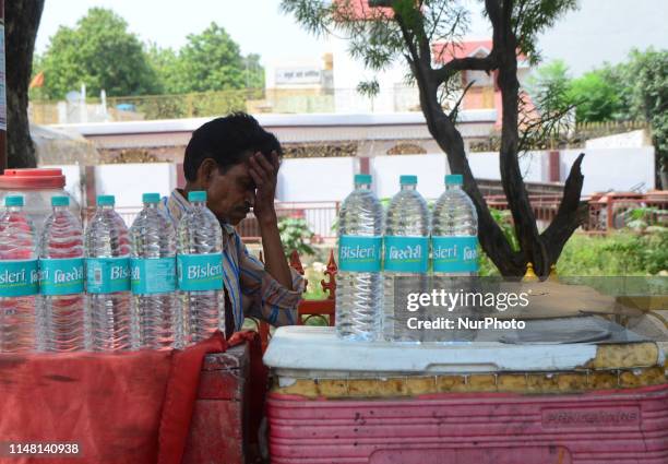 An indian vendor takes a nap in his drinking water bottle cart during a hot day in the outskirts of Allahabad on June 5, 2019 . Temperatures passed...