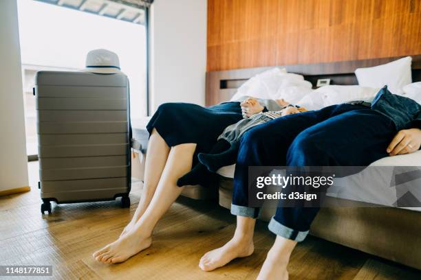 legs of family of three lying on bed in hotel room while on vacation - tired couple stock pictures, royalty-free photos & images