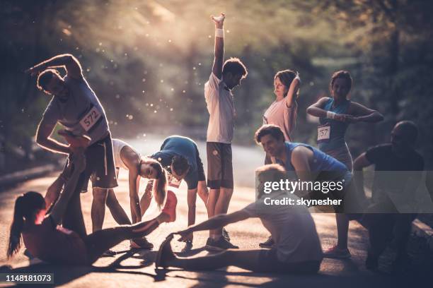 grote groep van lopers opwarming op een weg bij zonsondergang voor de marathon. - athleticism stockfoto's en -beelden