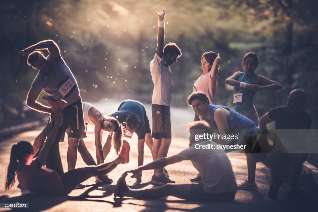 Large group of runners warming up on a road at sunset before the marathon.