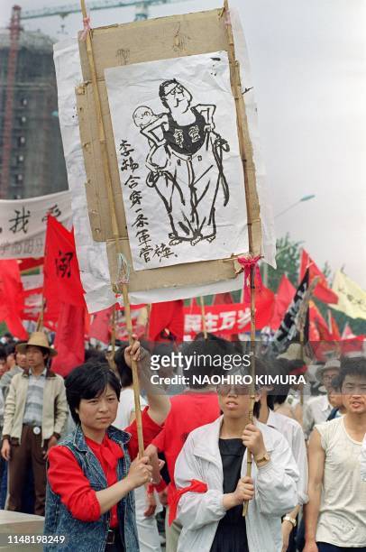 Chinese demonstrators raise a cartoon poster saying "Li and Yang dress in one pair of military controlled trouvers" on May 28, 1989 on the Beijing's...