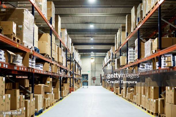 empty warehouse, view down the asile with shelves and boxes. - storage room stock pictures, royalty-free photos & images