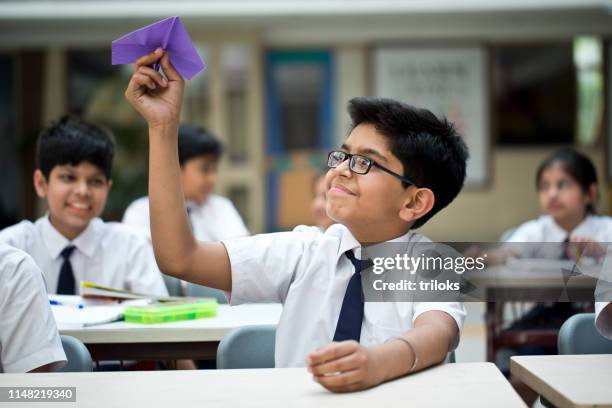 ragazzo che lancia un aereo di carta in classe - indian society and culture foto e immagini stock