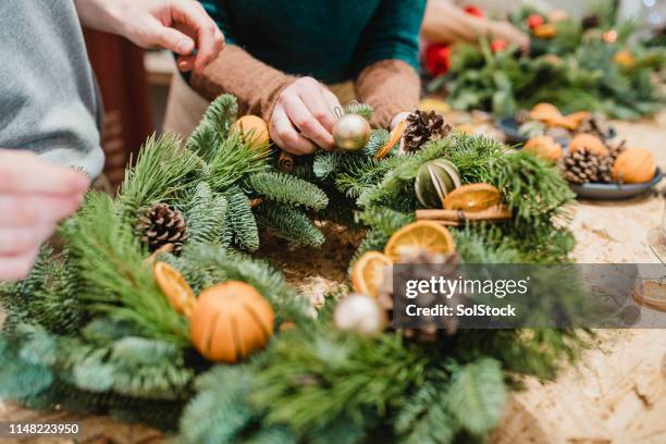 floristas diseñando una guirnalda de navidad - preparación fotografías e imágenes de stock