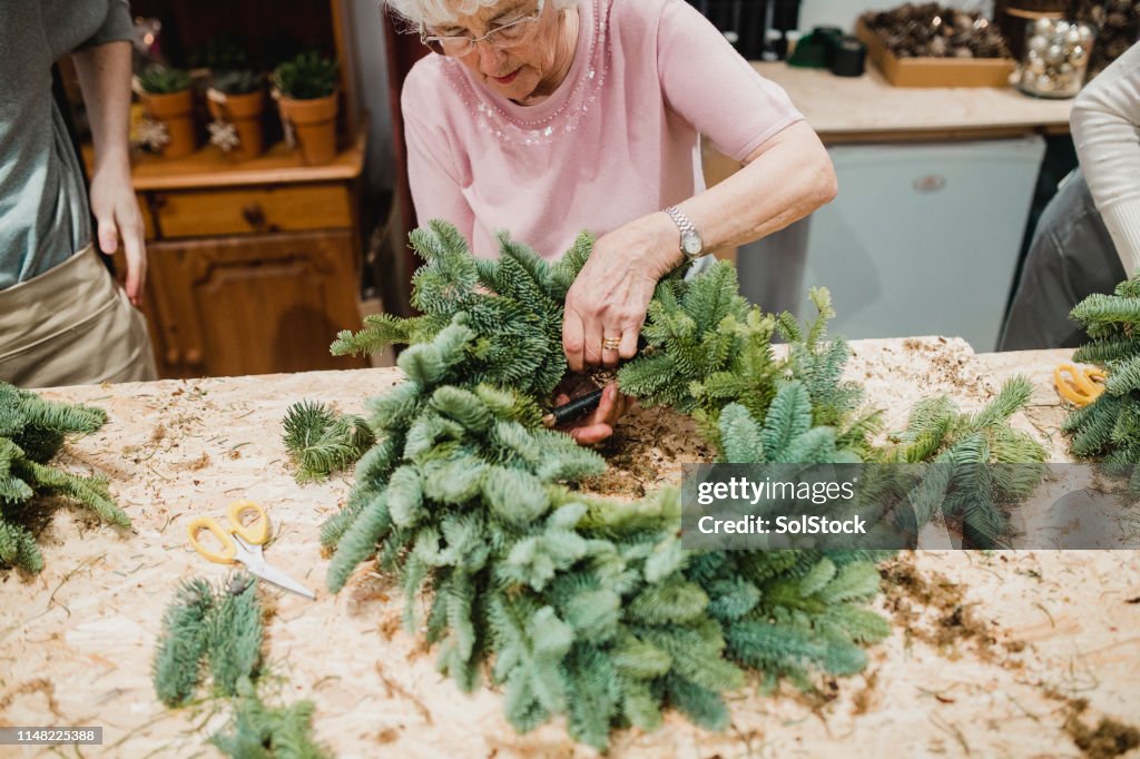 Mujer mayor haciendo una guirnalda de Navidad