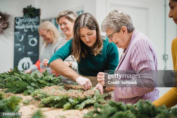assistance from a professional in a wreath-making workshop - wreath making stock pictures, royalty-free photos & images
