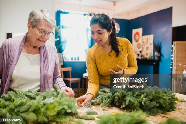 senior woman in a wreath making workshop - wreath making stock pictures, royalty-free photos & images