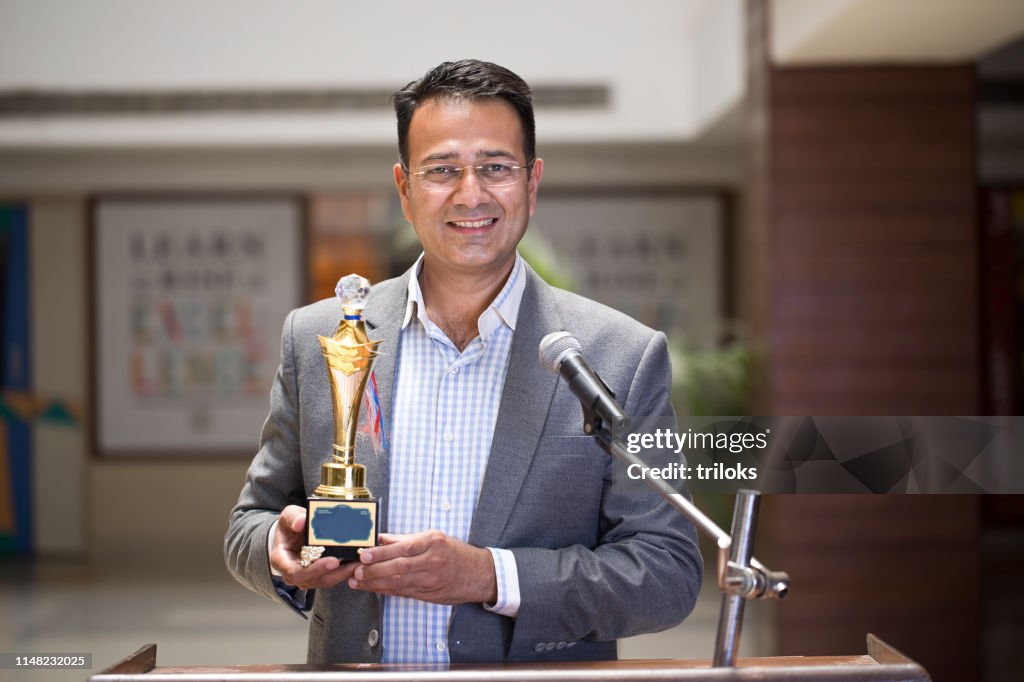 Teacher raising trophy and giving speech