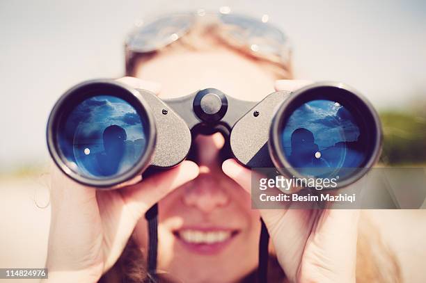 woman looking through binocular - binoculars imagens e fotografias de stock