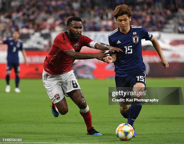 Yuya Osako of Japan dribbles the ball under the pressure from Khaleem Hyland of Trinidad and Tobago during the international friendly match between...