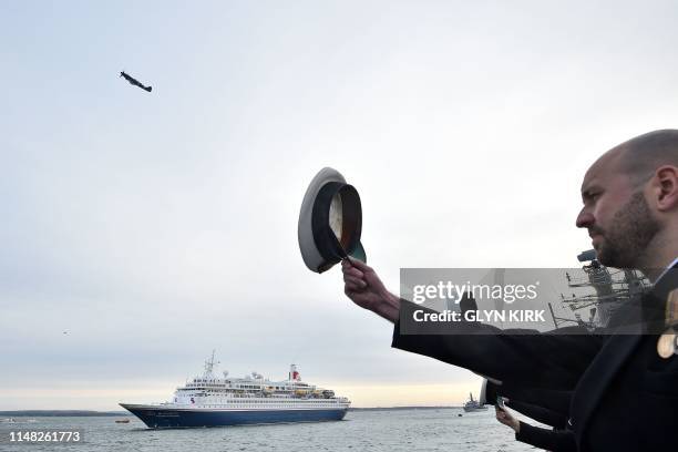 Spitfire flies overhead as crew from HMS Northumberland salute as they take part in a sail past to honour D-Day veterans on board the Royal British...