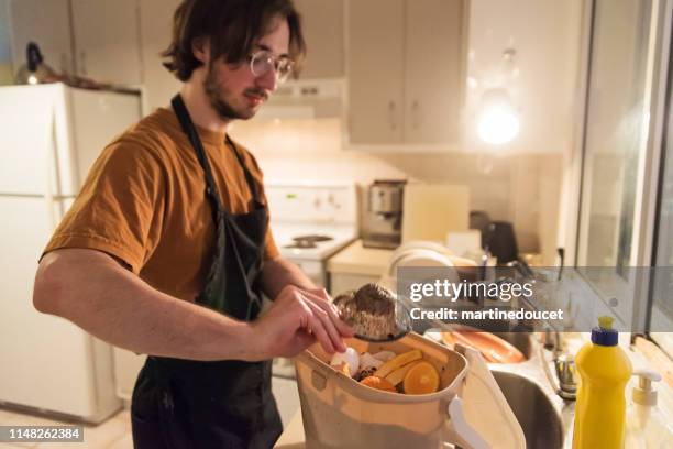 duizendjarige man zetten organisch afval in compost bin. - leftovers stockfoto's en -beelden