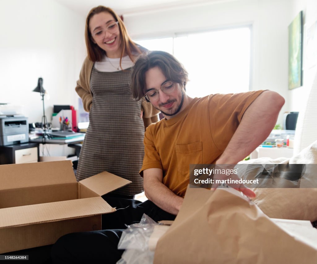 Pareja Millennial abriendo un paquete entregado en la sala de estar.