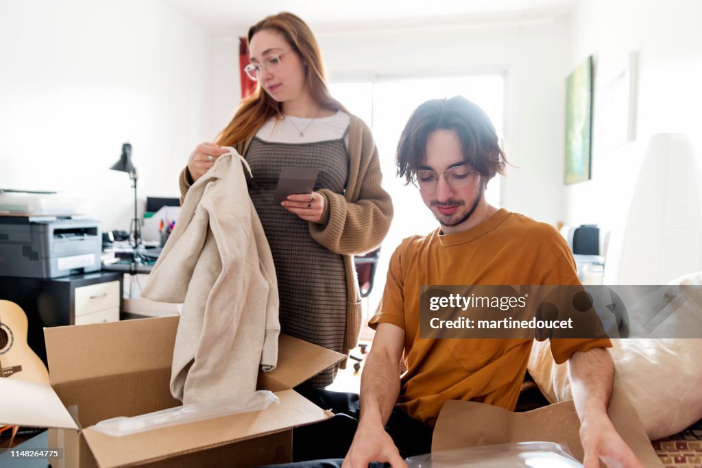 Duizendjarige paar het openen van een geleverd pakket in de woonkamer.