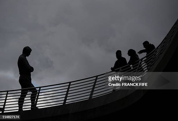 People watch the statue of late English football player Bobby Moore displayed in front of Wembley stadium's entrance one on May 26, 2011 in London....