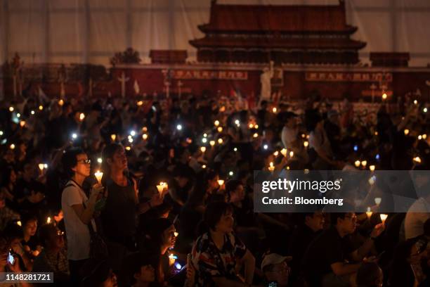 Attendees gather in front of a banner featuring Tiananmen Gate at Victoria Park during a candlelight vigil to commemorate the 30th anniversary of the...