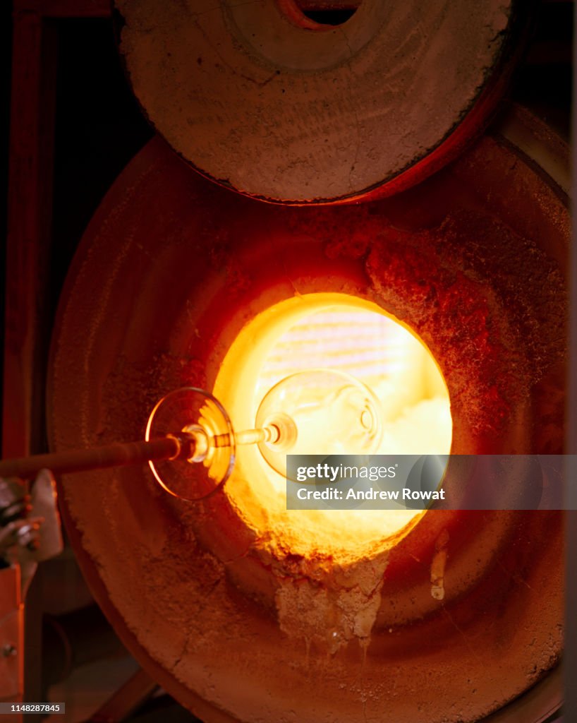 Wine glass being finished in kiln.