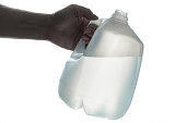Hand holding 1 gallon plastic bottle of drinking water